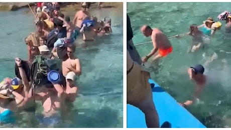 Turisti costretti a camminare in acqua per raggiungere la spiaggia: la vacanza in Grecia comincia con borse e zaini sulla testa